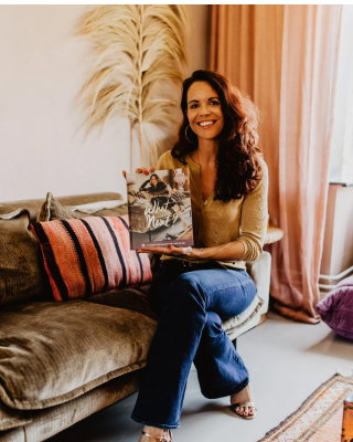 Sylvia sitting on sofa holding her book