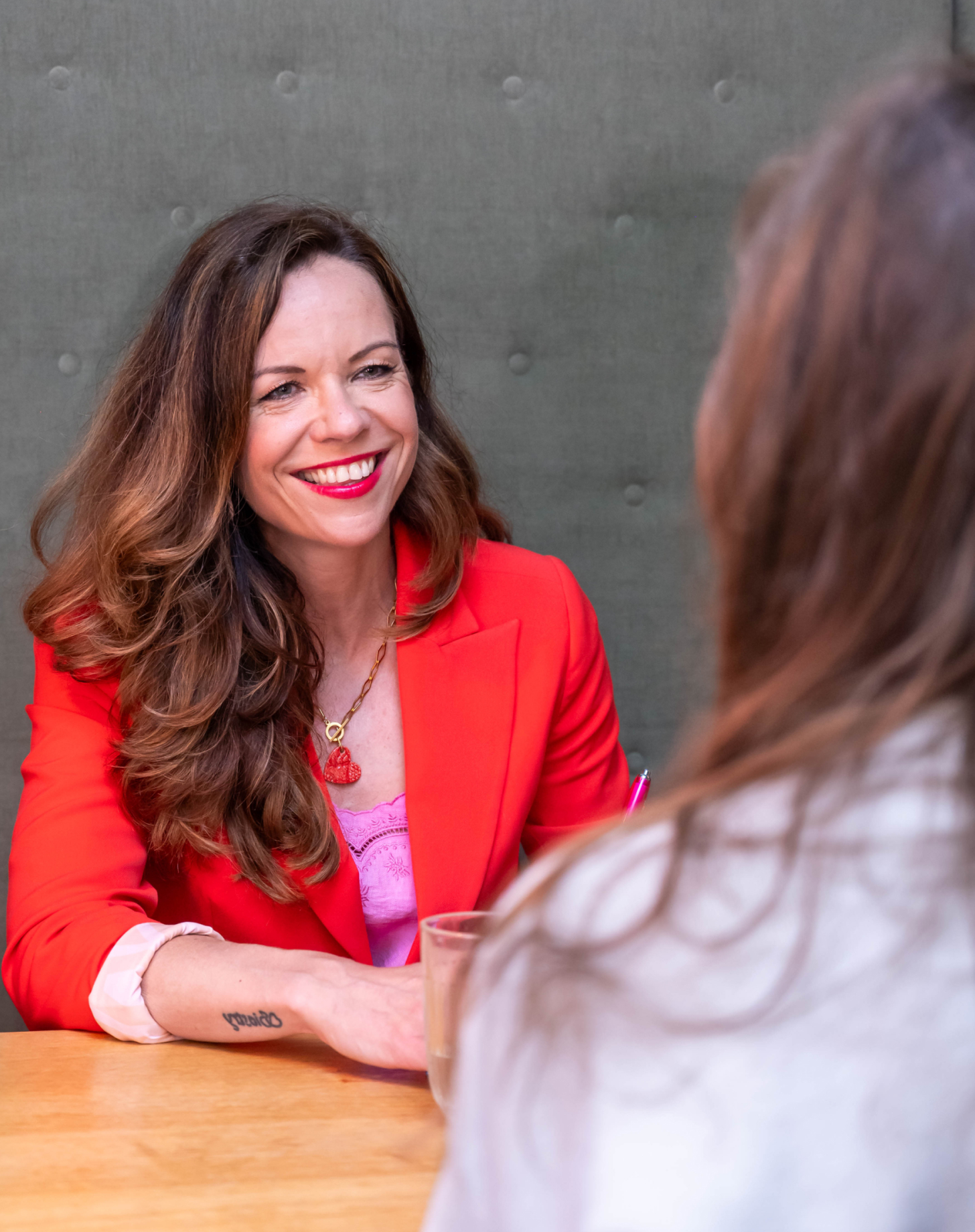 Sylvia in a red blazer having a conversation with another woman.