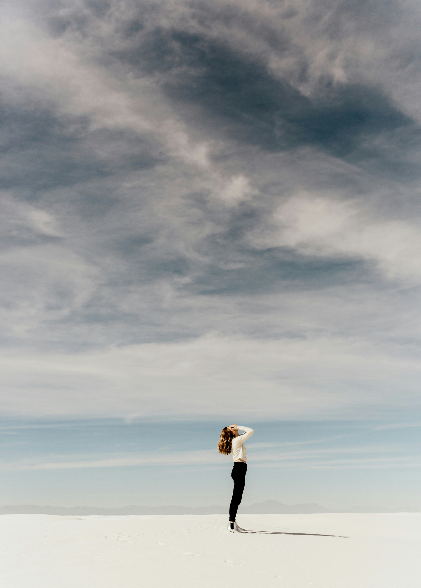 Woman stand along on beach with her hands to her hand with a stormy background